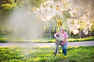 Beautiful senior woman with bicycle outside in spring nature.