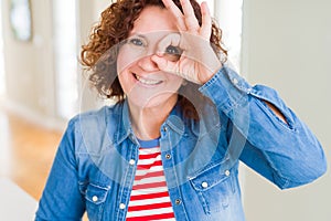 Beautiful senior woman doing ok gesture with hand smiling, eye looking through fingers with happy face