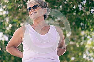 Beautiful senior woman gray-haired standing in outdoor public park smiling