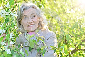 Beautiful senior woman posing near blooming tree