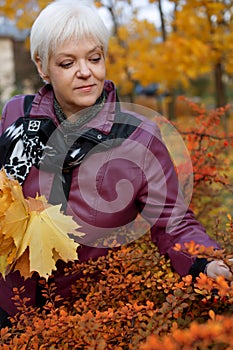 Beautiful senior woman relaxing in the fall park