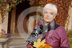 Beautiful senior woman relaxing in the fall park