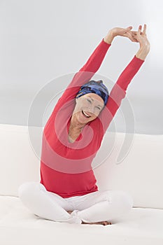 Beautiful senior woman relaxing at home in her bed arm up and s