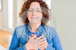 Beautiful senior woman smiling with hands on chest with closed eyes and grateful gesture on face
