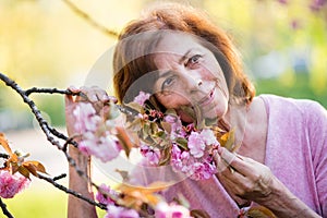 Beautiful senior woman standing outside in spring nature. Copy space.