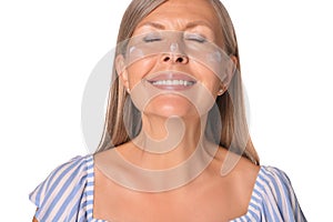 Beautiful senior woman with sun protection cream on her face isolated on white