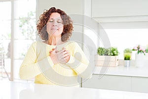Beautiful senior woman wearing yellow sweater smiling with hands on chest with closed eyes and grateful gesture on face