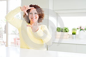 Beautiful senior woman wearing yellow sweater smiling making frame with hands and fingers with happy face