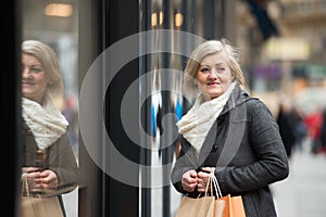 Beautiful senior woman window shopping in the city. Winter