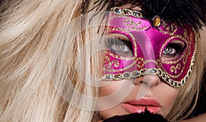 Beautiful sensual blonde woman with carnival mask , standing on a background of black balloons