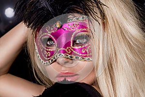 Beautiful sensual blonde woman with carnival mask , standing on a background of black balloons