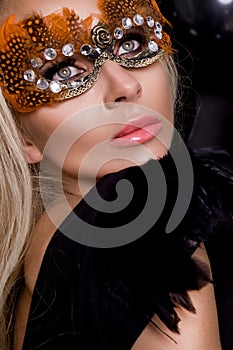 Beautiful sensual blonde woman with carnival mask , standing on a background of black balloons