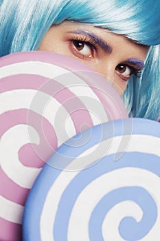 Beautiful sensual caucasian woman with exotic appearance in blue wig and colorful red lips, closing her with two big pink and blue