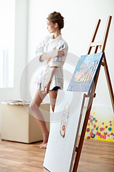 Beautiful sensual female artist posing in her art studio, sitting on chair.