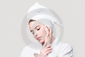 Beautiful sensual woman apply skincare cream on face, happy young woman wrap towel on head put facial creme on doing