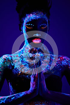 beautiful sensual woman of black appearance in fluorescent paint makeup, posing