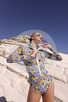 beautiful sensual woman with dark hair in elegant printed beach clothes posing in the white rock beach on Cyprus