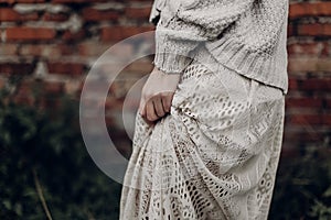 Beautiful sensual woman in stylish boho indie clothes, wool sweater and white lace dress, hands closeup