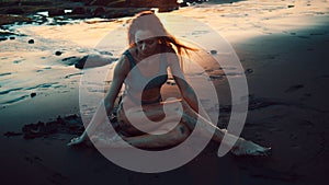 Beautiful sensual woman in swimsuit at the black sand beach during sunset