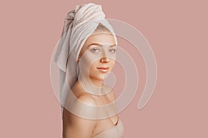 Beautiful sensual young girl with clean skin on a pink background with a mockup. Topless woman in a towel. The concept of spa