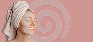 Beautiful sensual young girl with clean skin on a pink background with a mockup. Topless woman in a towel. The concept of spa