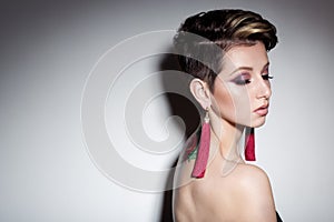 Beautiful sensual young girl with short hair with bright makeup in the nude, beautiful evening jewelry earrings, necklaces, b