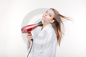 Beautiful sensual young woman in bathrobe drying hair with dryer