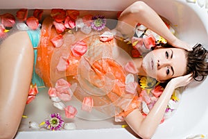 Pretty girl taking a bath with flower petals