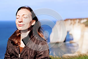 Woman mindfulness smiling doing breath exercises on top of normandy cliffs in the spring