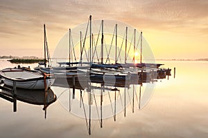 Beautiful serene sunrise over lake with yachts