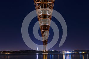 Beautiful and serene view of the Tagus River and the 25 of April Bridge Ponte 25 de Abril at night, in Lisbon, Portugal