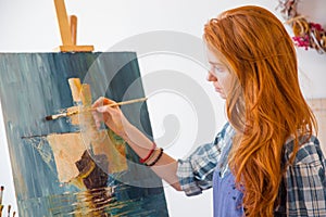 Beautiful serene young female painter painting picture in art workshop