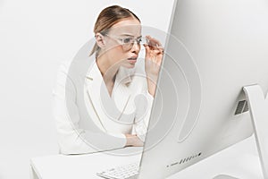 Beautiful serious amazing woman sitting  over white wall background using pc computer