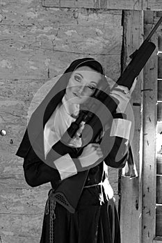 Beautiful serious angry nun holding a rifle, gun. Picture of a girl with a gun. Dangerous nun holding gun.