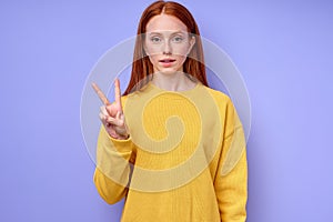 beautiful serious redhead woman demonstrating letter V sign language