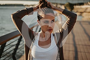 Beautiful woman fixing hair bun by the river