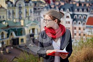 Hermoso grave una mujer en chaqueta a anteojos el lee un libro contra verano edificios 