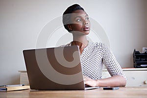 Beautiful serious woman sitting at desk with laptop