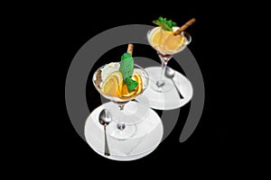 Beautiful serving of scoops of ice cream with slices of orange and mint, ice cream in a glass and saucer with a spoon on a black