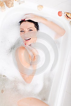 Beautiful sexual attractive young woman sensual girl lying relaxing and enjoying in the spa bath with foam happy smiling