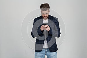 Beautiful sexy bearded man with a beautiful haircut with a phone in his hand. The employee is seriously copied with the boss,
