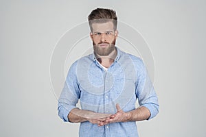 A beautiful sexy bearded man in casual clothes holds his crossed hands and looks thoughtfully at the camera. he stands photo