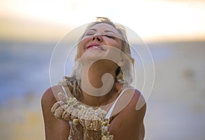 Beautiful and sexy blond hair woman in bikini posing happy and relaxed at tropical beach in holidays getaway trip playing with wet