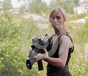 Beautiful blond woman holding army weapon