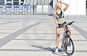 Beautiful, sexy blonde woman with long hair posing in outdoor with bike