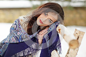 Beautiful brunette girl in a blue scarf in the winter on a