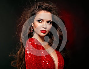 Beautiful sexy brunette in red dress with healthy curly hair and glamour makeup. Fashion Beauty Girl  on black studio