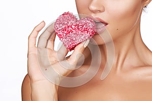 Beautiful brunette woman eating cake shape of heart on a white background, healthy food, tasty, organic, romantic valentine d