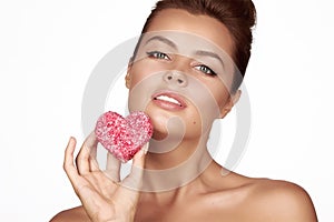 Beautiful brunette woman eating cake shape of heart on a white background, healthy food, tasty, organic, romantic valentine d