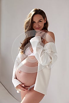 Beautiful sexy brunette woman pregnant belly lady on nine`s month happy Mather white skin wear white underwear and jacket on ligh